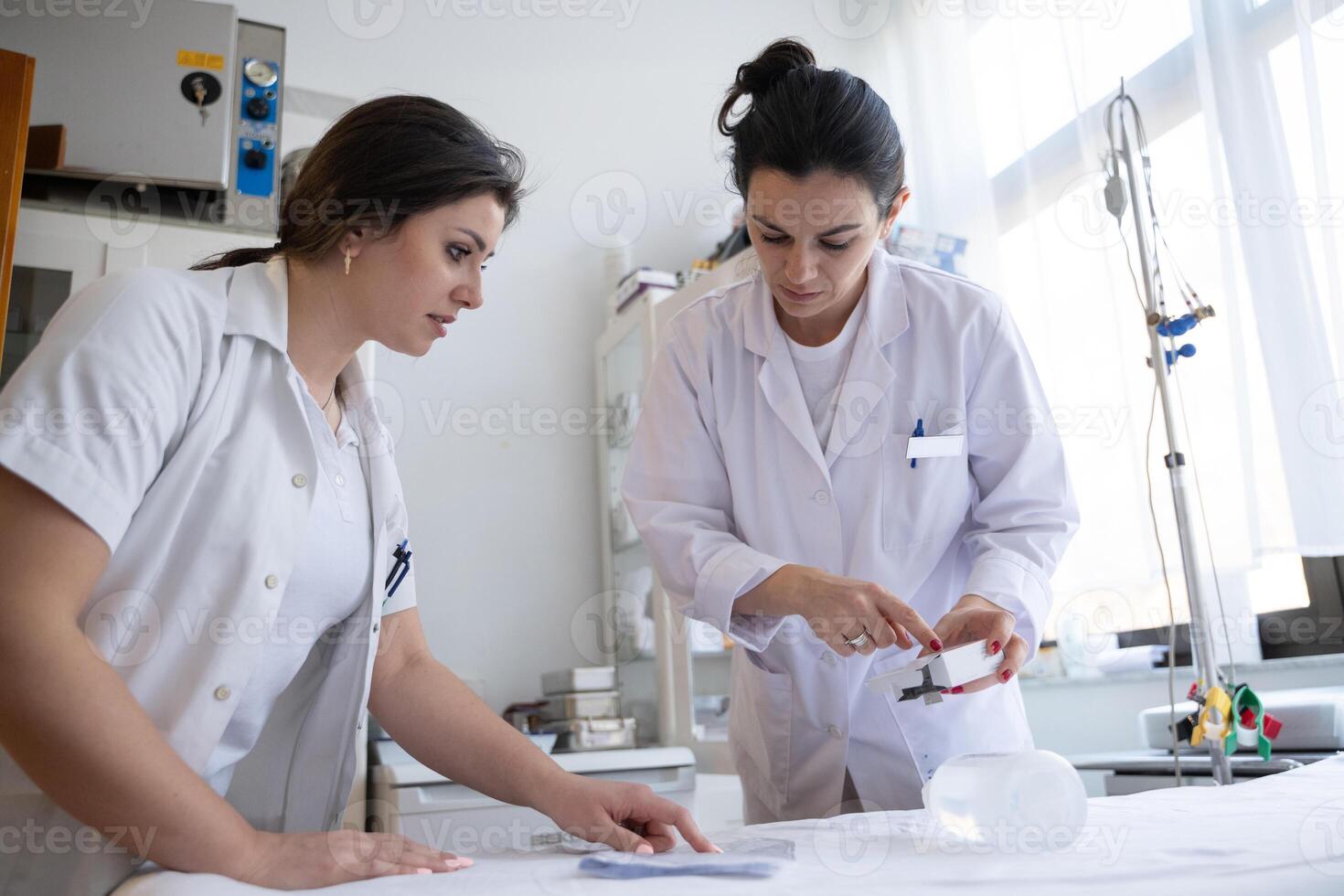Two nurses in a hospital laboratory are carefully inspecting and preparing medications for patients and hospital use. photo