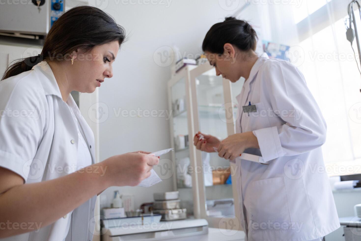 Two nurses in a hospital laboratory are carefully inspecting and preparing medications for patients and hospital use. photo