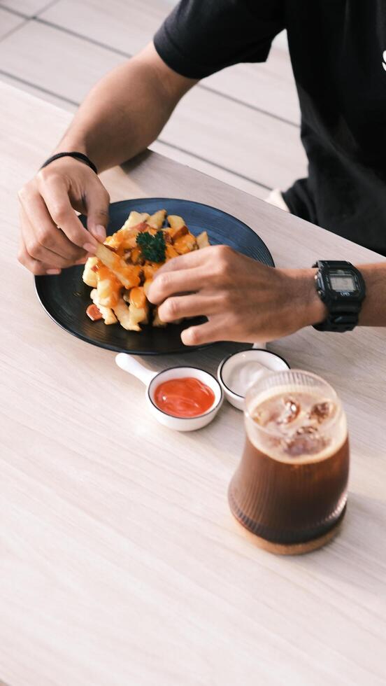 a person eating fries with a drink and a cup of coffee photo