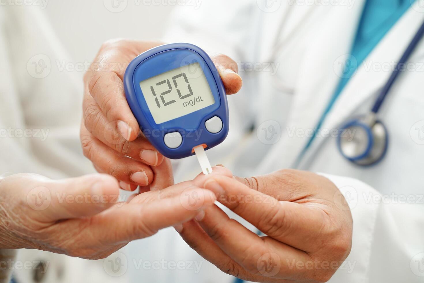 Asian doctor using digital glucose meter for check sample blood sugar level to treatment dia photo