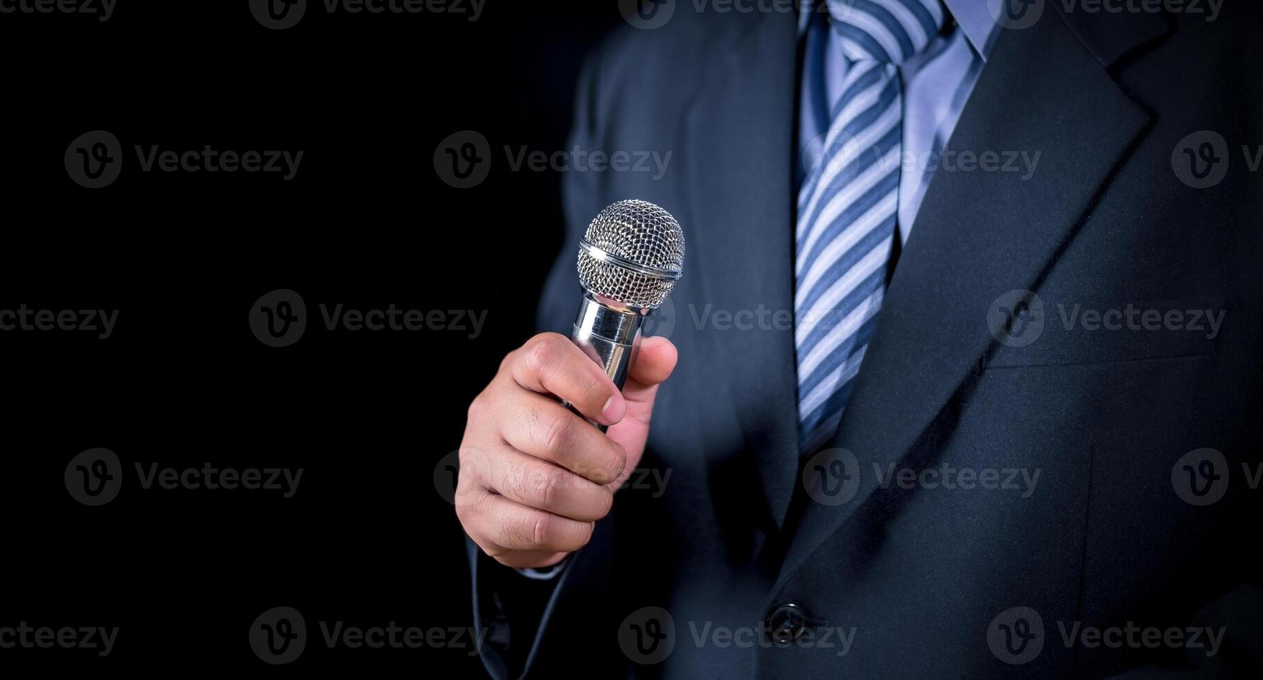 Man in business suit holding a microphone conducting a business interview, journalist reporting, public speaking, press conference, MC, Public speaking and giving speech in suit photo