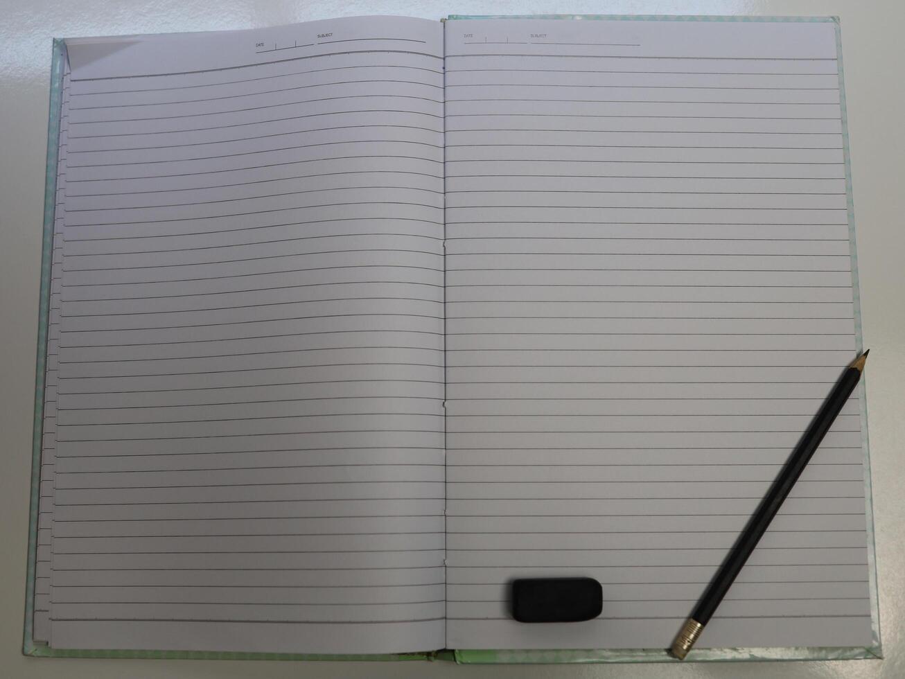Blank notebook with pencil and eraser on white table photo