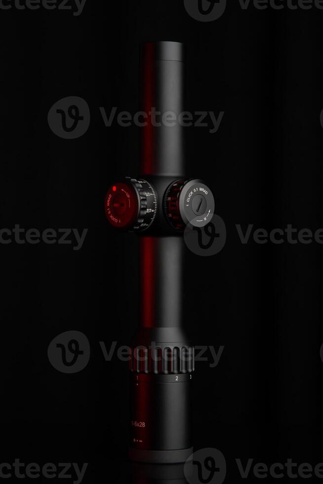 A stylish rifle scope in black with red accents, showcasing precision adjustment controls and magnification scales, against a deep, dark background. photo