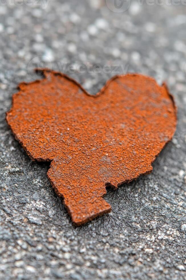 Rusty heart shape found on pavement, symbolizing love and resilience in urban environments. photo