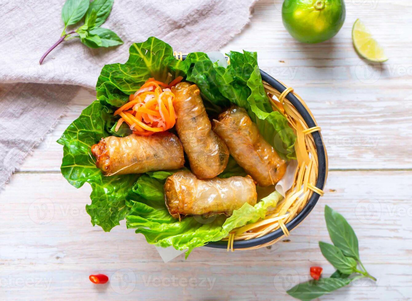 Vietnamese Fried Spring Rolls with lemon served in basket isolated on wooden background top view of Hong Kong food photo