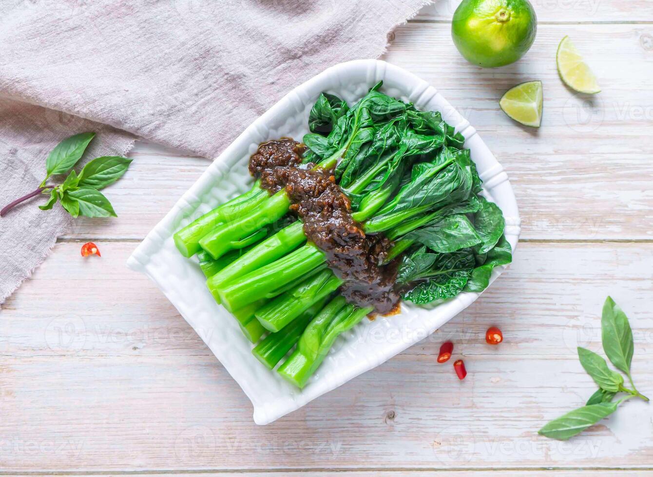 Chinese Broccoli or gai lan with Oyster Sauce with lemon served in plate isolated on wooden background top view of Hong Kong food photo