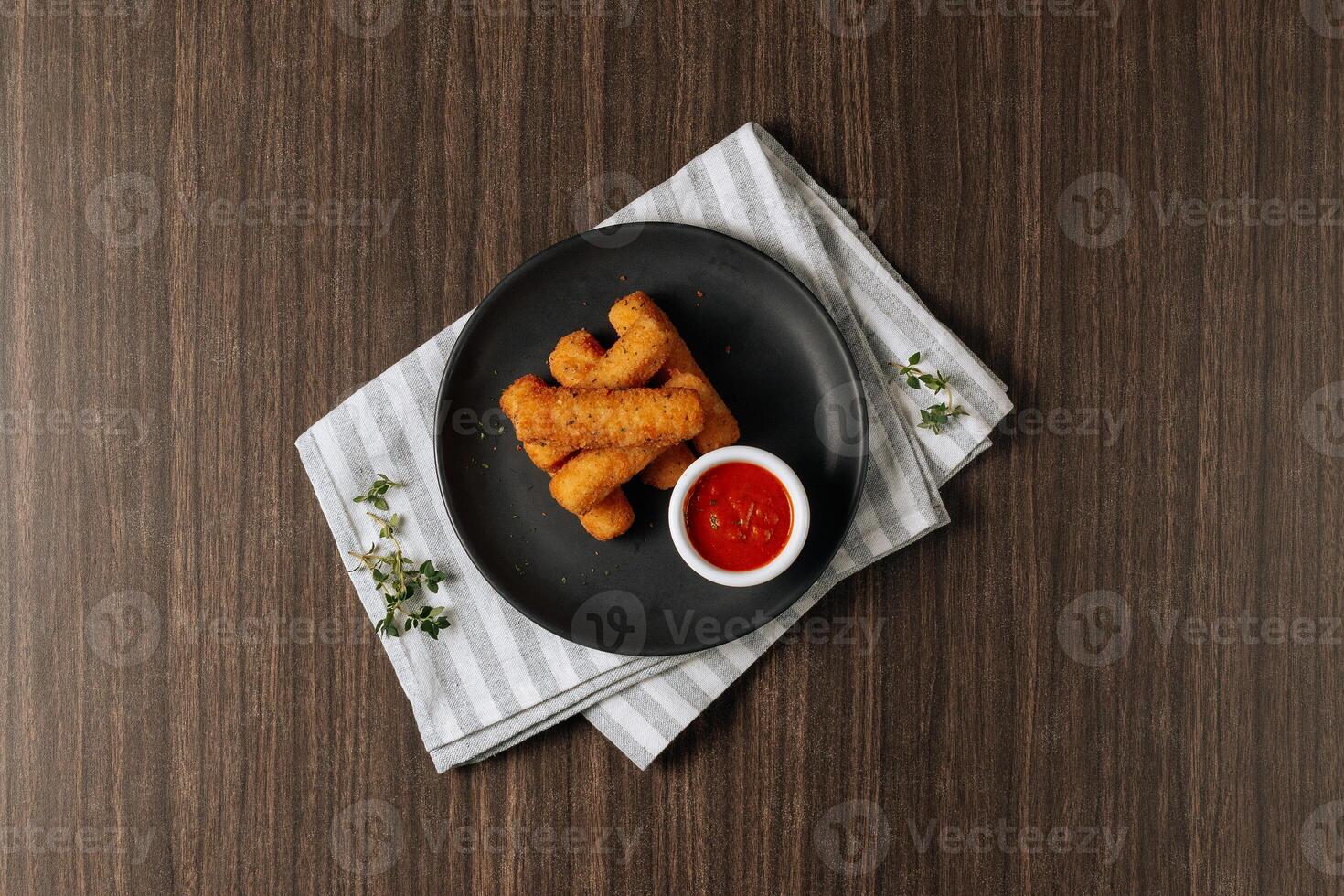 Deep fried crispy mozzarella cheese sticks with tomato dipping sauce isolated on wooden table top view photo