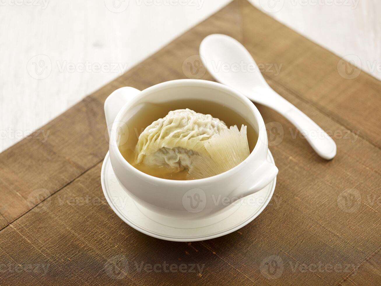 Double boiled Sharks Fin Dumpling Soup served in a bowl with spoon isolated on mat side view on grey background thailand fast food photo