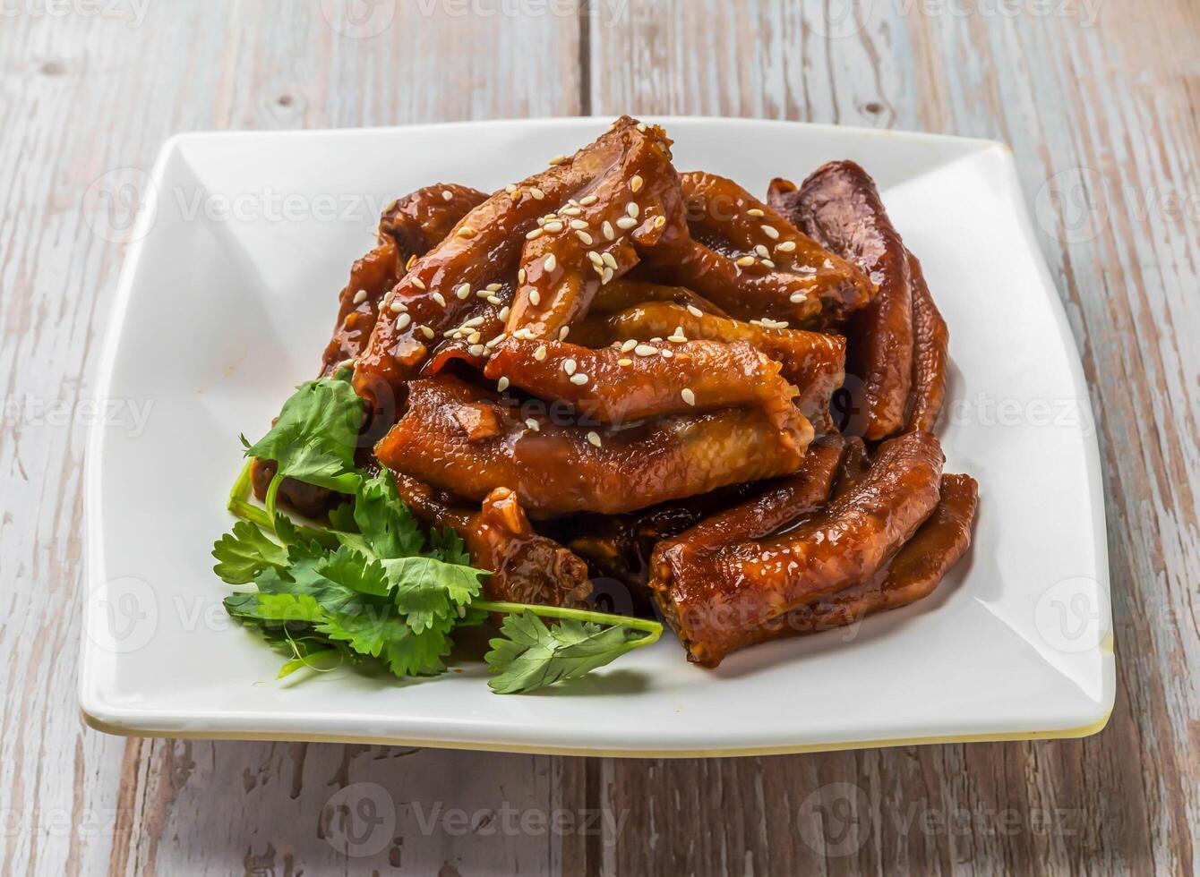 Braised Duck Feet with savory sauce, sesame seeds and cilantro served in plate on Wood Table Close up Side view of Hong Kong food photo