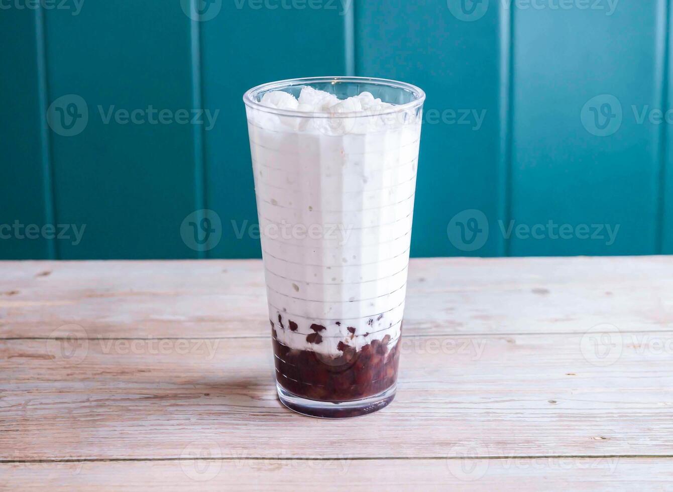 Iced red bean with coconut milk with ice cube served in glass isolated on wooden background side view of Hong Kong drink photo