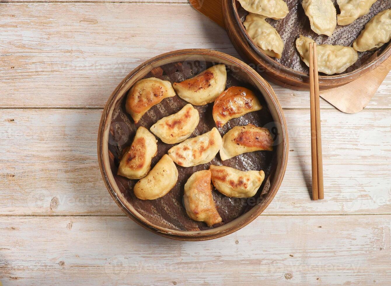 Handmade fried dumplings with steamed dumpling or momo served in wooden dish with chopsticks isolated on table top view Japanese food photo