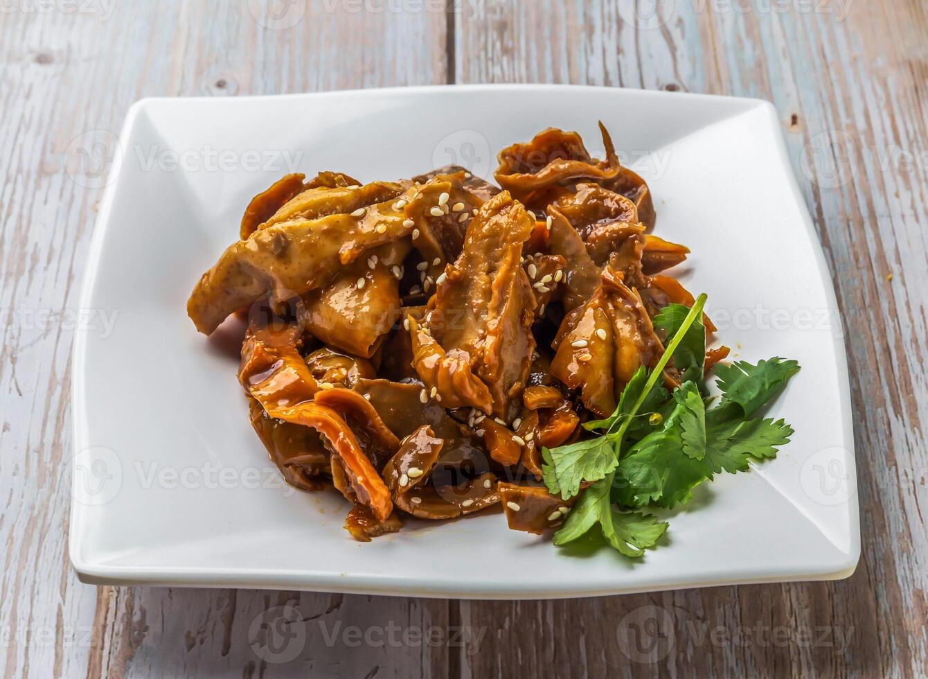 Braised Pig Stomach with rich sauce, sesame seeds and cilantro served in plate on Wood Table Close up Side view of Hong Kong food photo