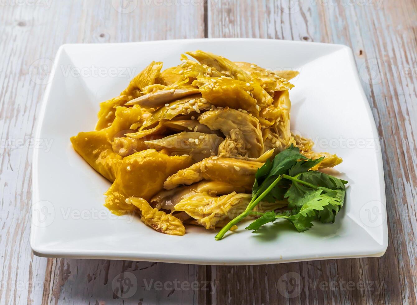 Salt Baked Shredded Chicken with savory sauce, sesame seeds and cilantro served in plate on Wood Table Close up Side view of Hong Kong food photo