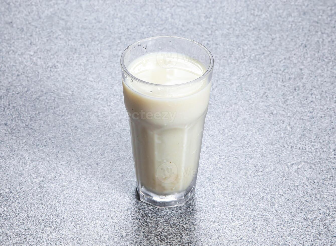 Homemade soy milk served in glass dish isolated on stone background side view of Asian Hong Kong drink photo