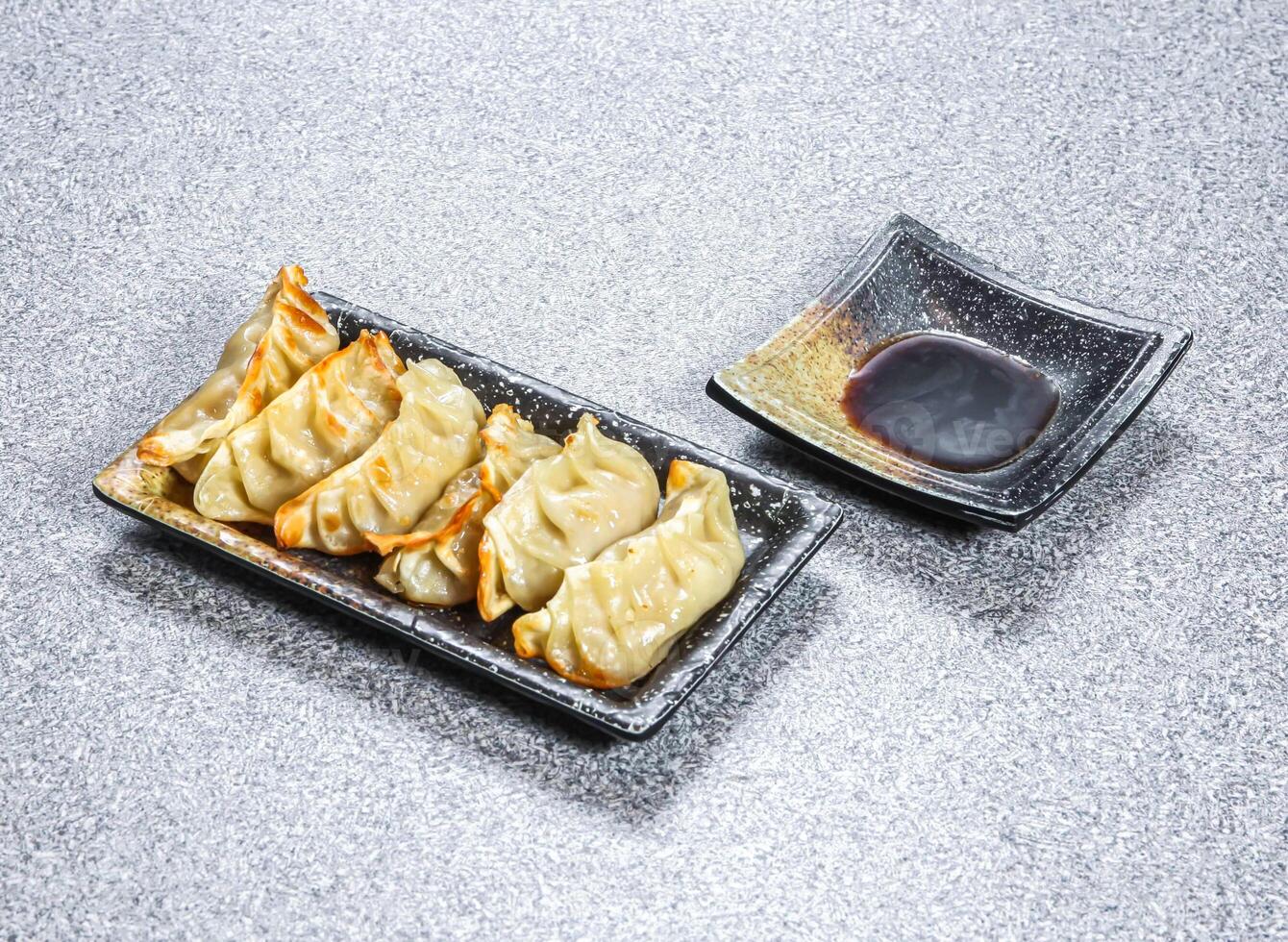 Moon Fried Dumplings Gyoza with dipping sauce served in tray dish isolated on stone background side view of Asian Dim Sum Hong Kong photo