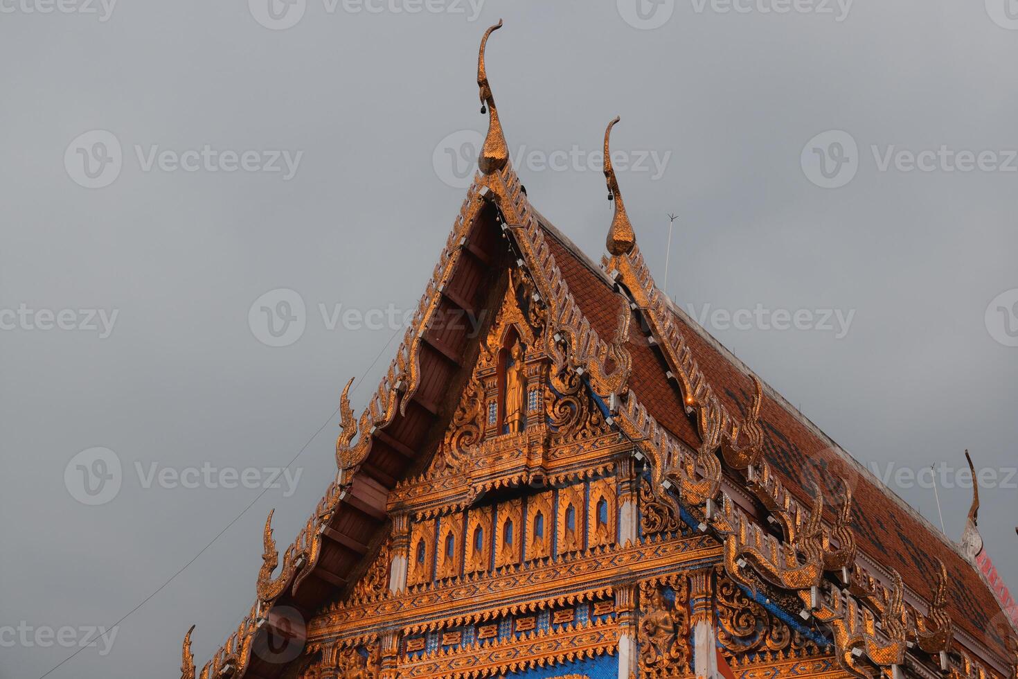 An Intricate Design of a Thai Temple Roof Set Beautifully Against a Cloudy Sky Background photo