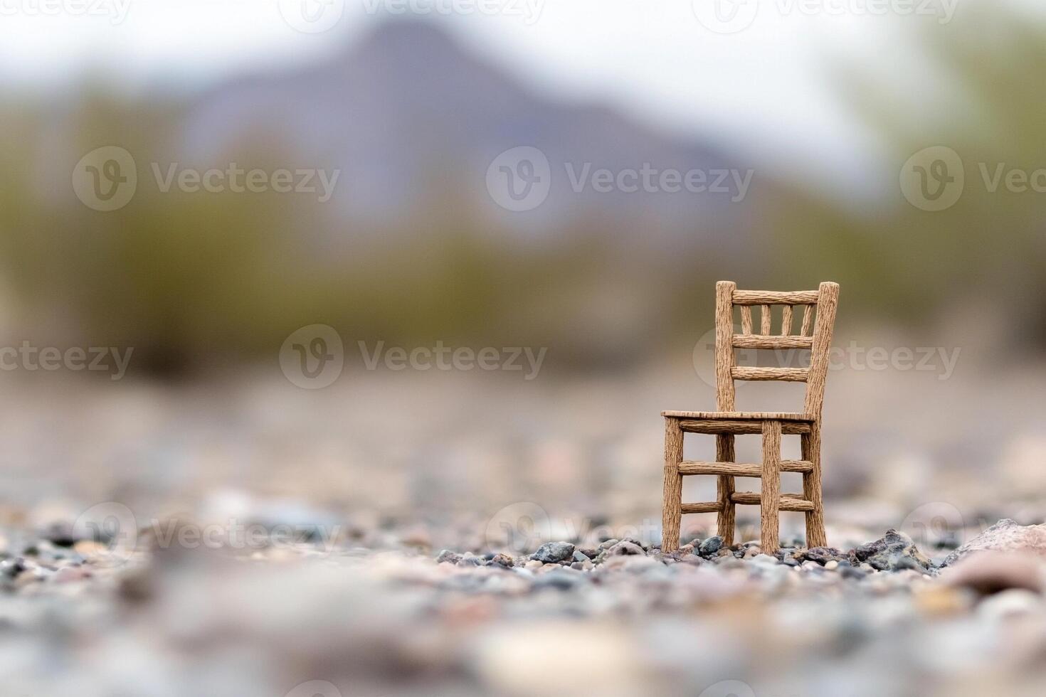 A miniature wooden chair sits on the ground in a desert photo