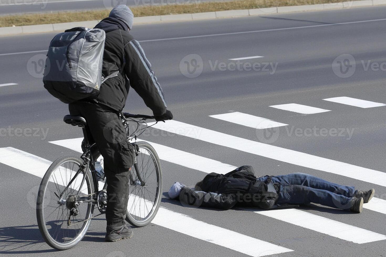 A man on a bike is standing next to a man laying on the ground photo