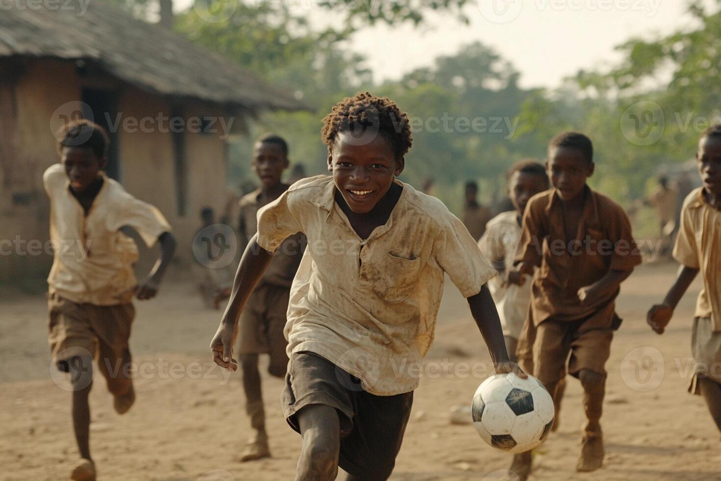 A group of boys playing soccer in a dirt field photo