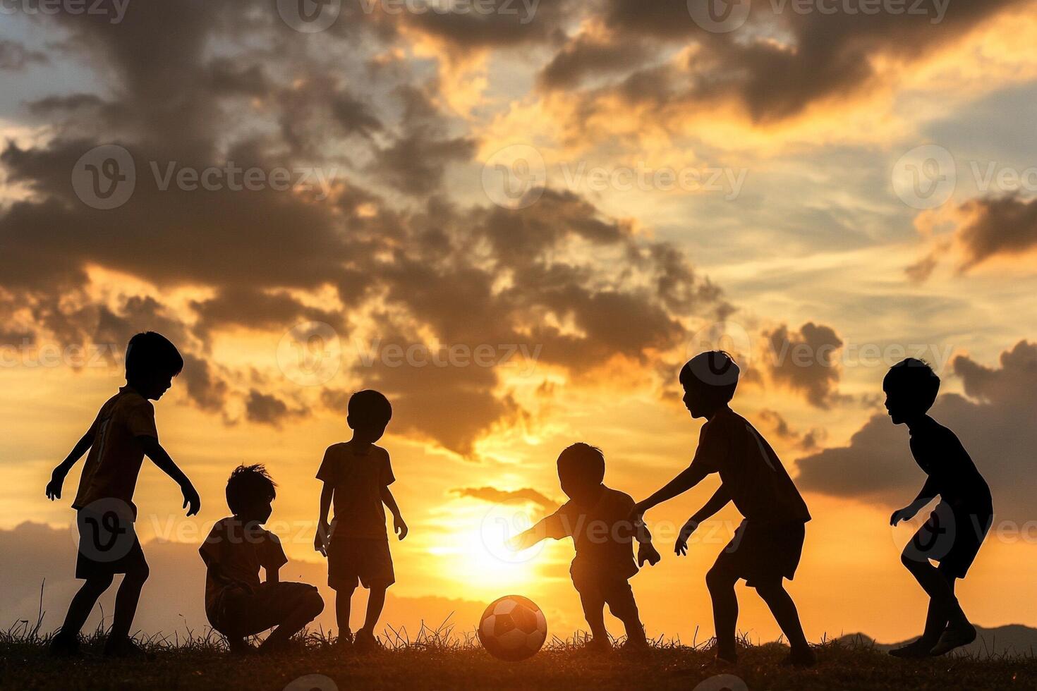 Silhouette of children playing soccer at sunset photo
