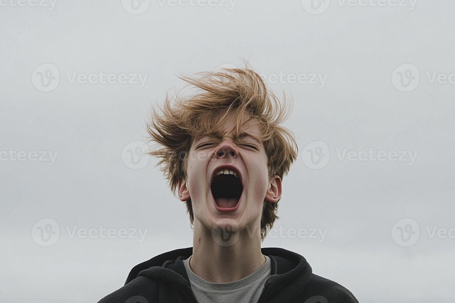 A young man with his mouth open and his hair blowing in the wind photo