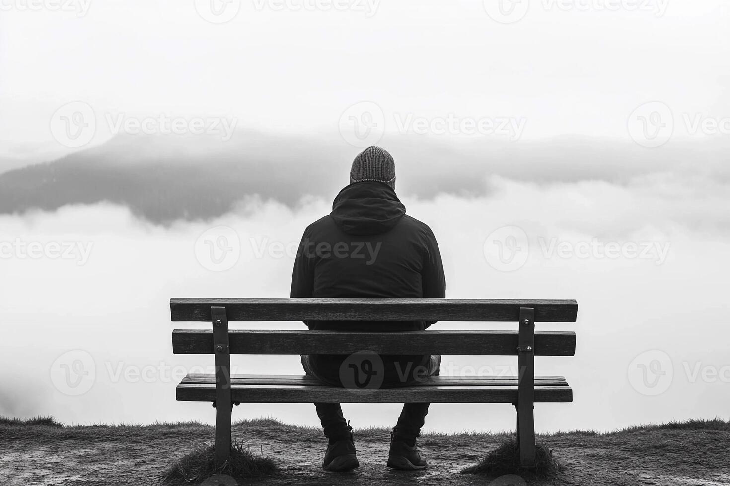 Man sitting on bench looking out over the clouds photo