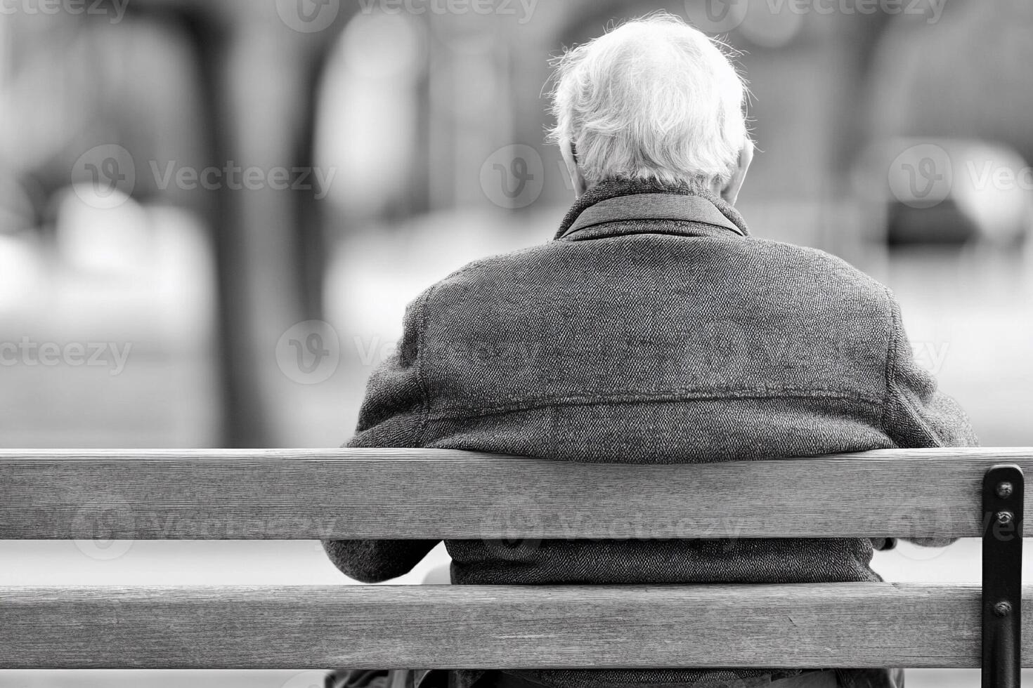 An elderly man sitting on a bench in a park photo