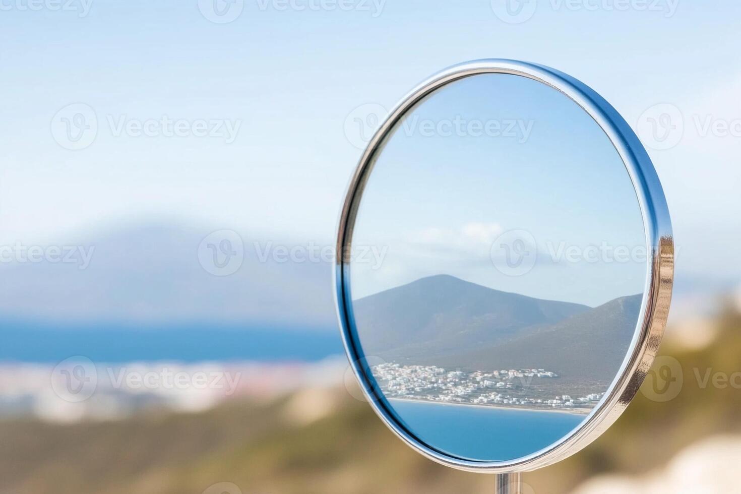 A circular mirror with a view of a mountain and city photo