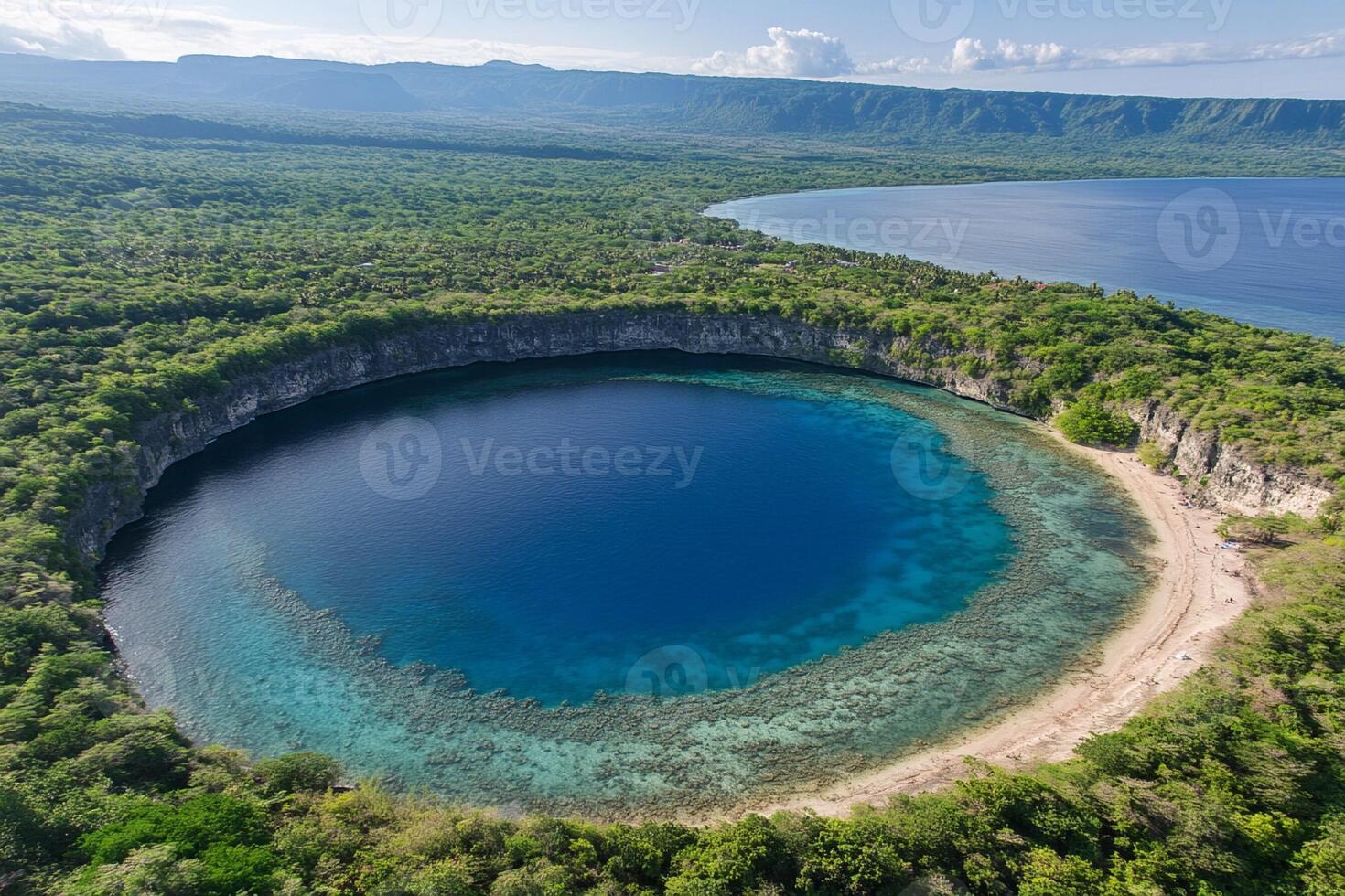 The blue hole in the middle of the lake is surrounded by lush green trees photo