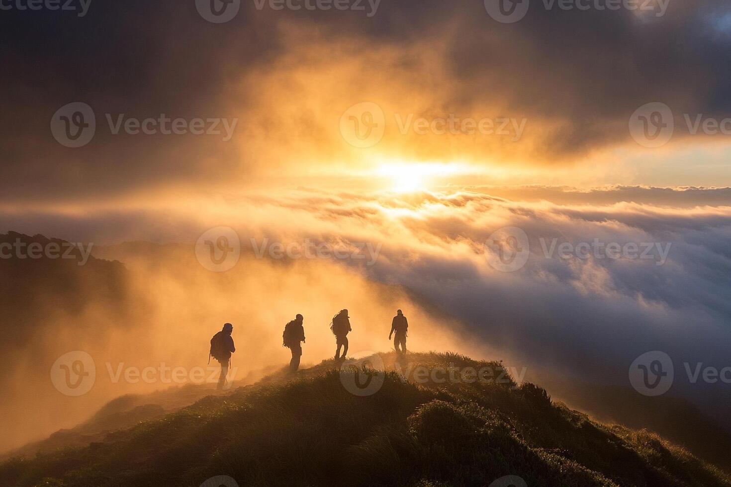 Three people stand on top of a mountain at sunset photo