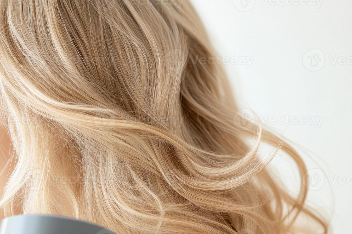 A woman with long blonde hair using a blow dryer photo