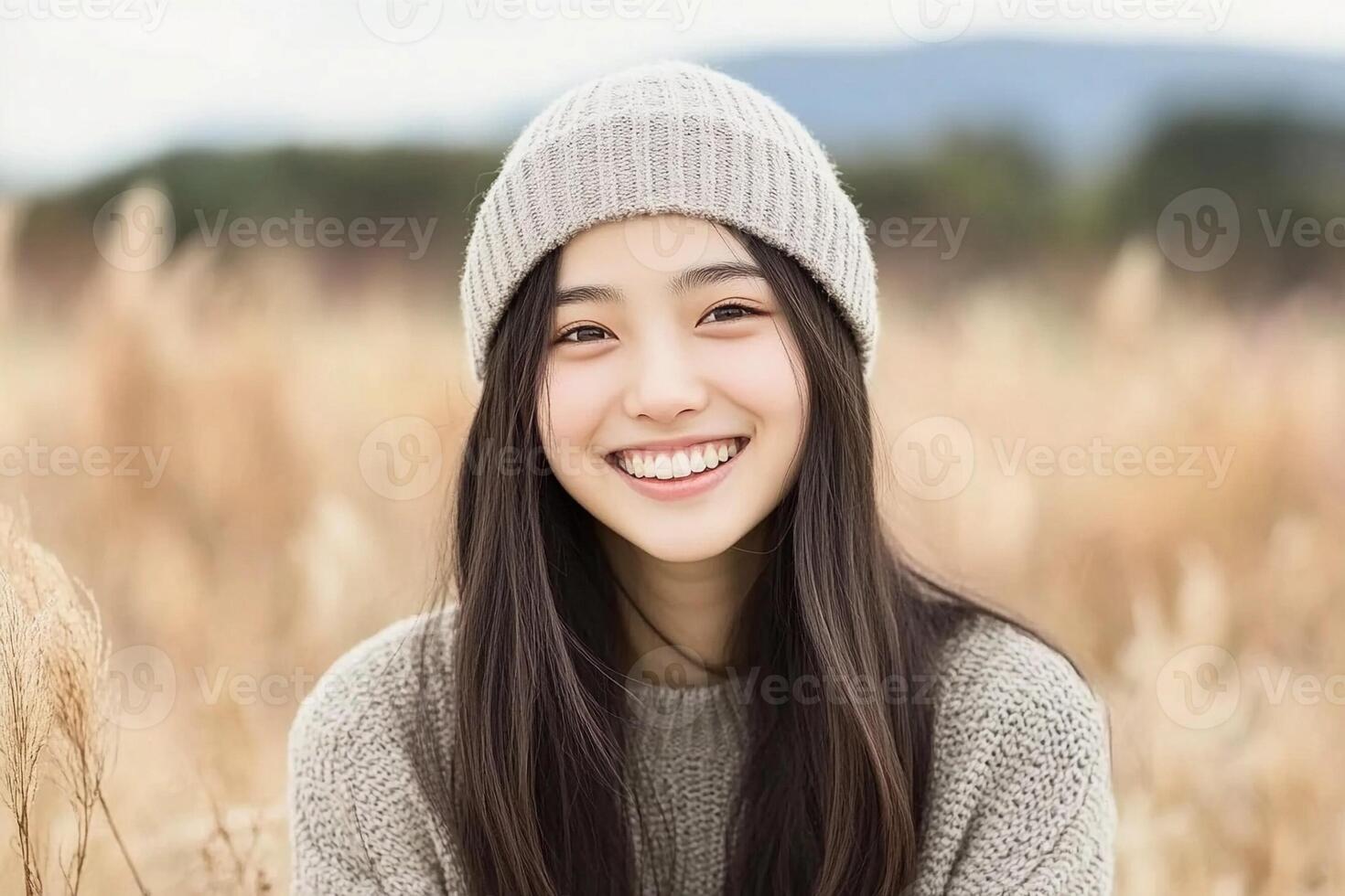 A young woman in a beanie smiling in a field photo