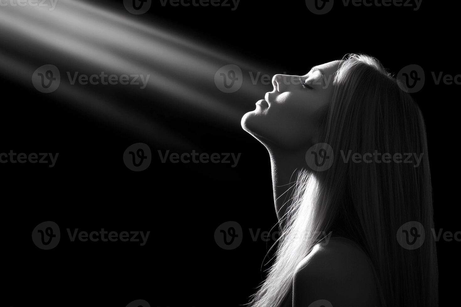 A woman is looking up at the sun with her eyes closed photo