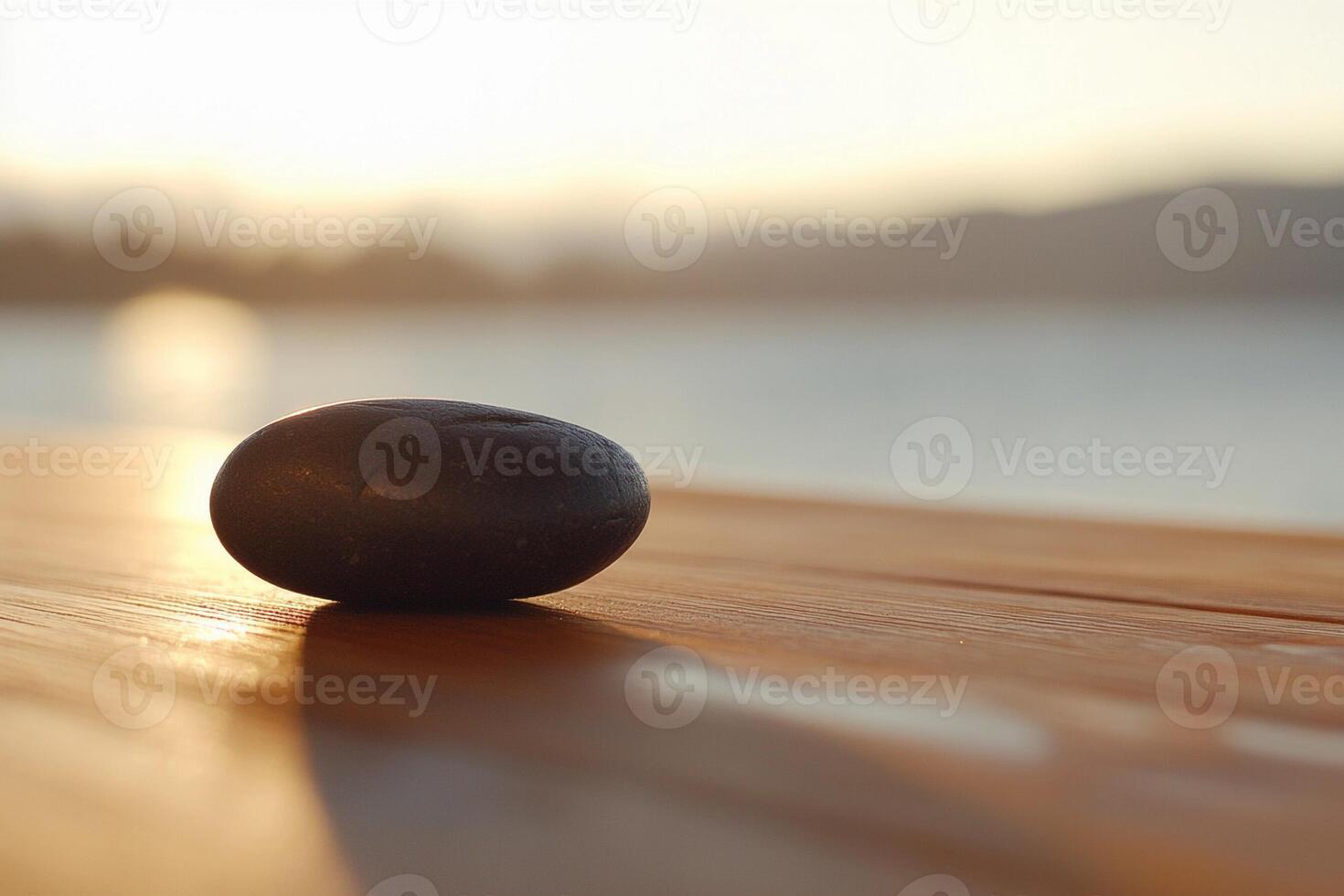 A stone sits on a wooden table in front of a lake photo