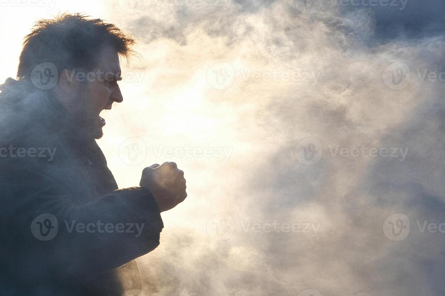 A man is standing in the smoke with his fist up photo