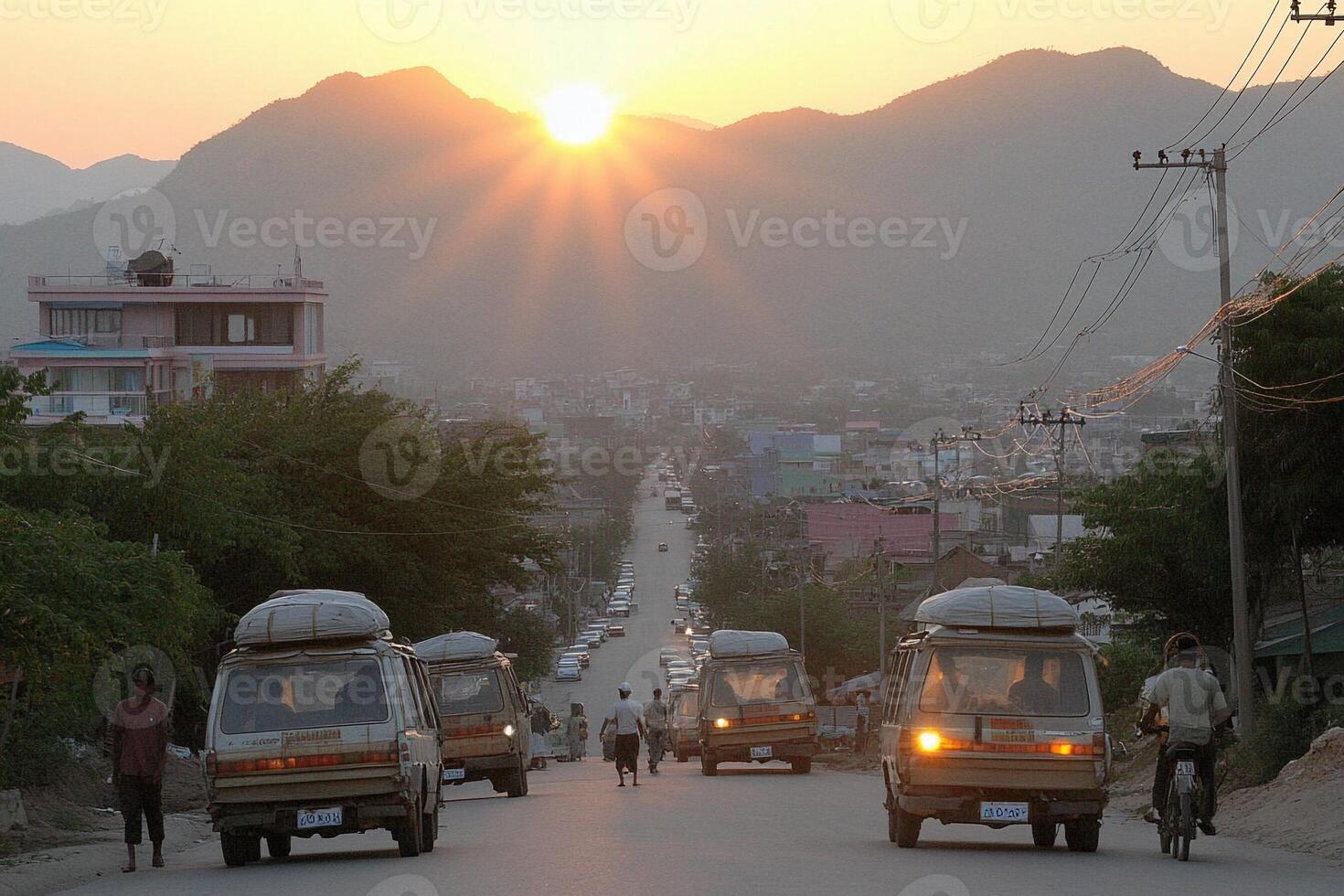 A group of vehicles driving down a street at sunset photo