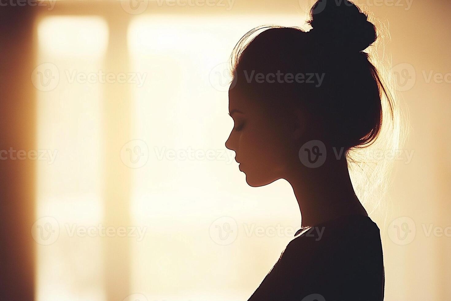 A woman in silhouette standing in front of a window photo