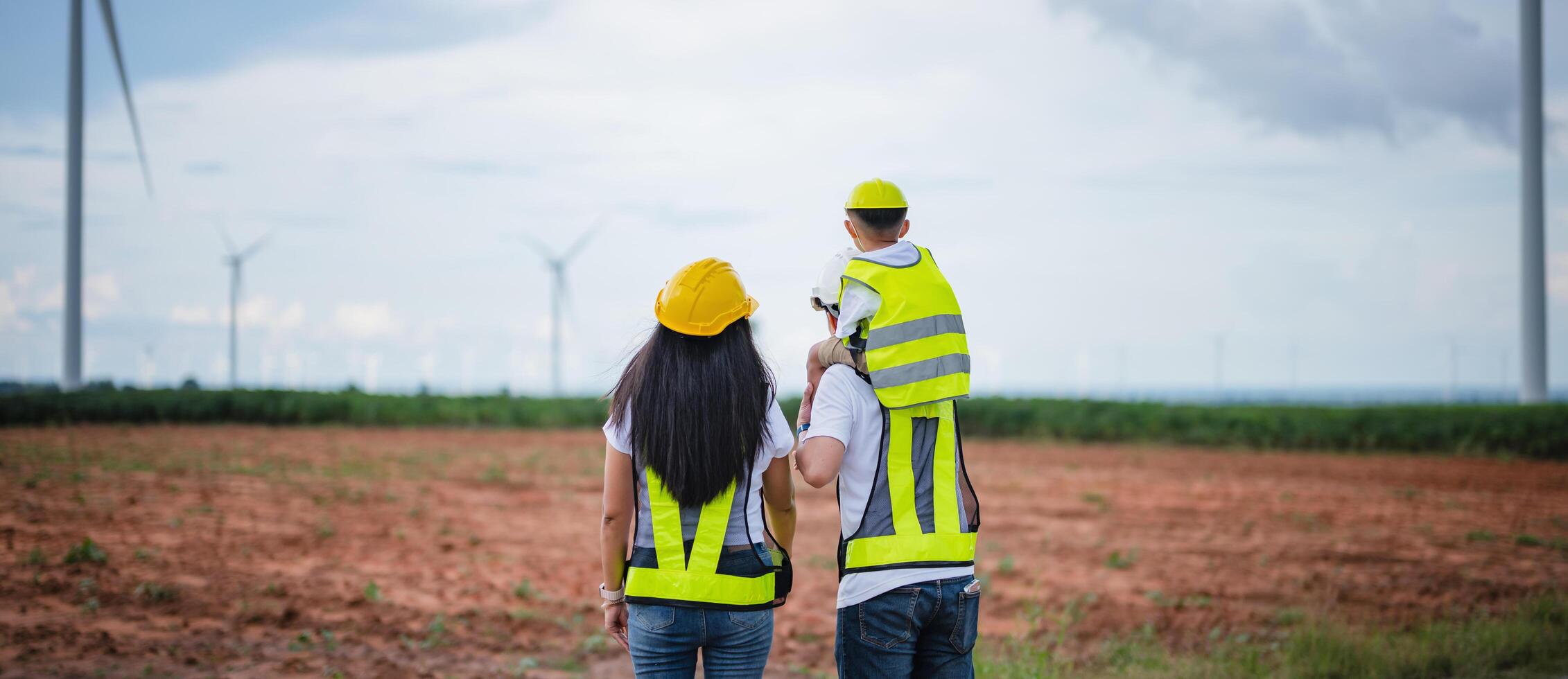 family of three, a man, a woman and a child, are walking through a field photo