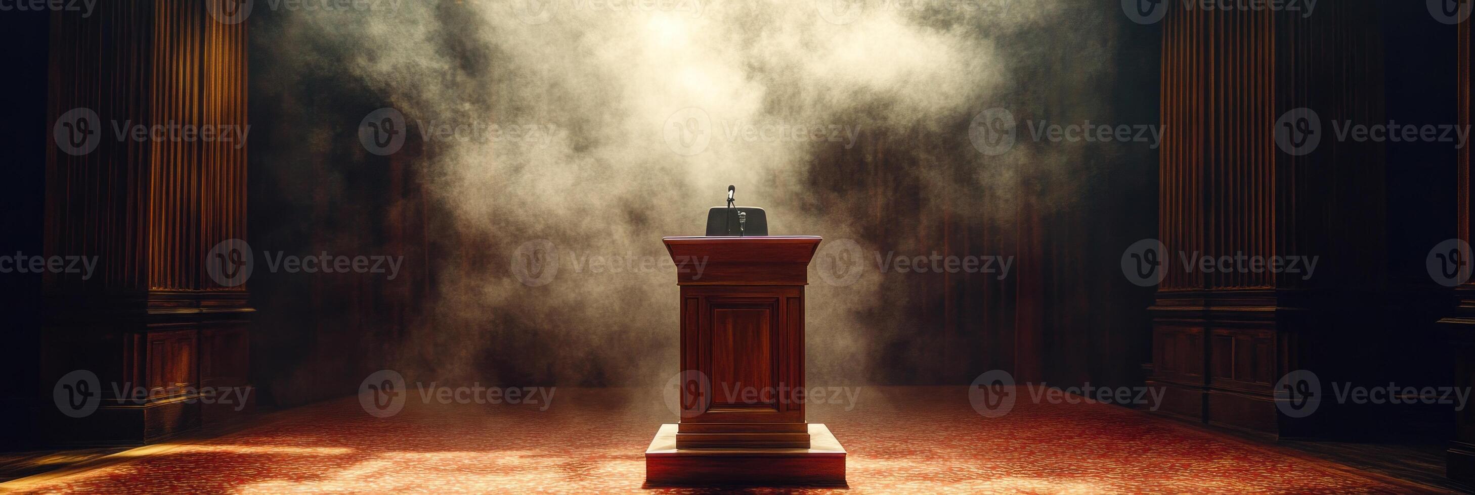 A wooden podium stands at the center of a dimly lit hall, surrounded by swirling smoke. The mysterious ambiance invites anticipation and curiosity about the upcoming event photo