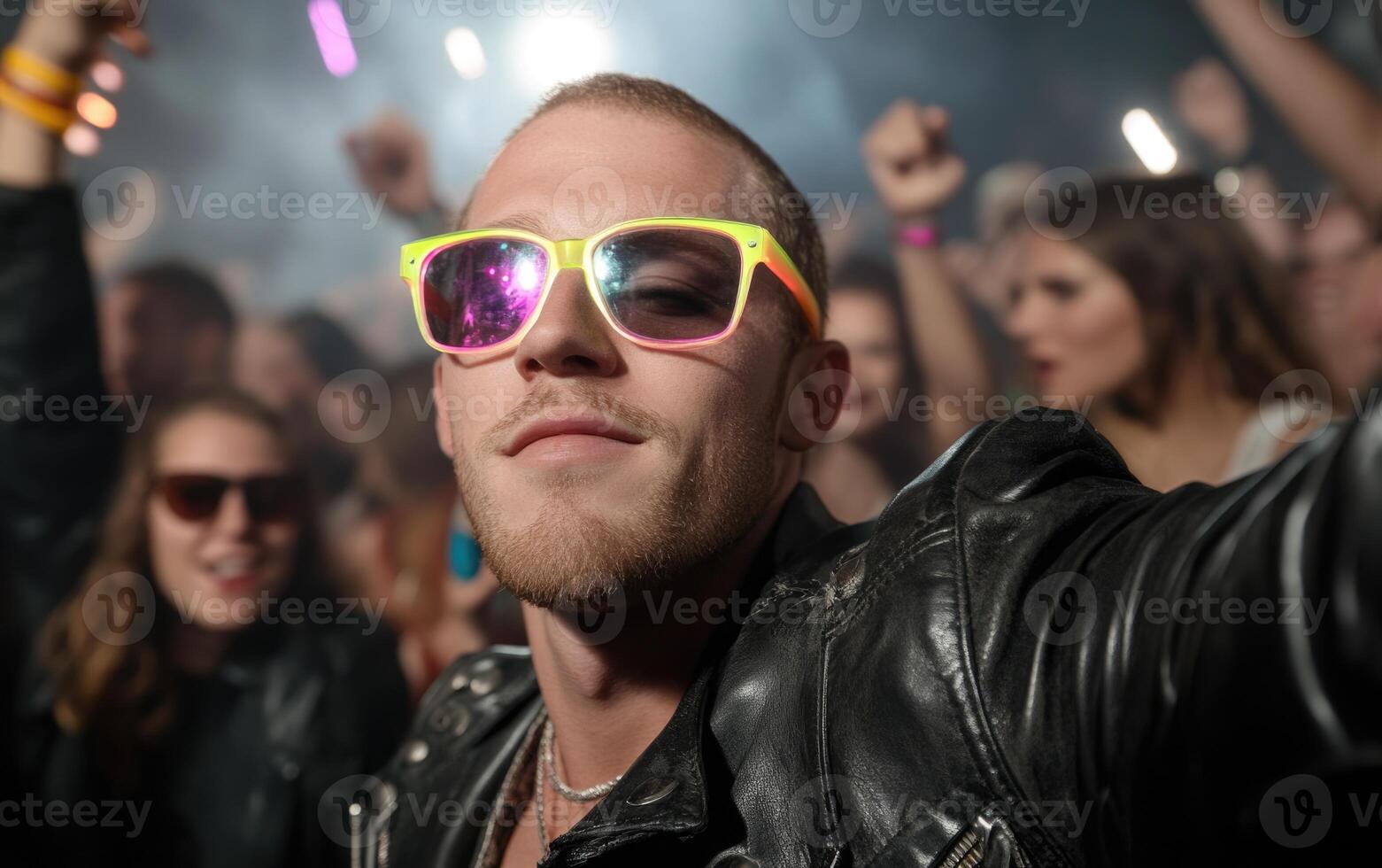 A stylish individual wears colorful sunglasses and poses confidently while surrounded by an energetic crowd at a lively nighttime event, creating a festive mood photo