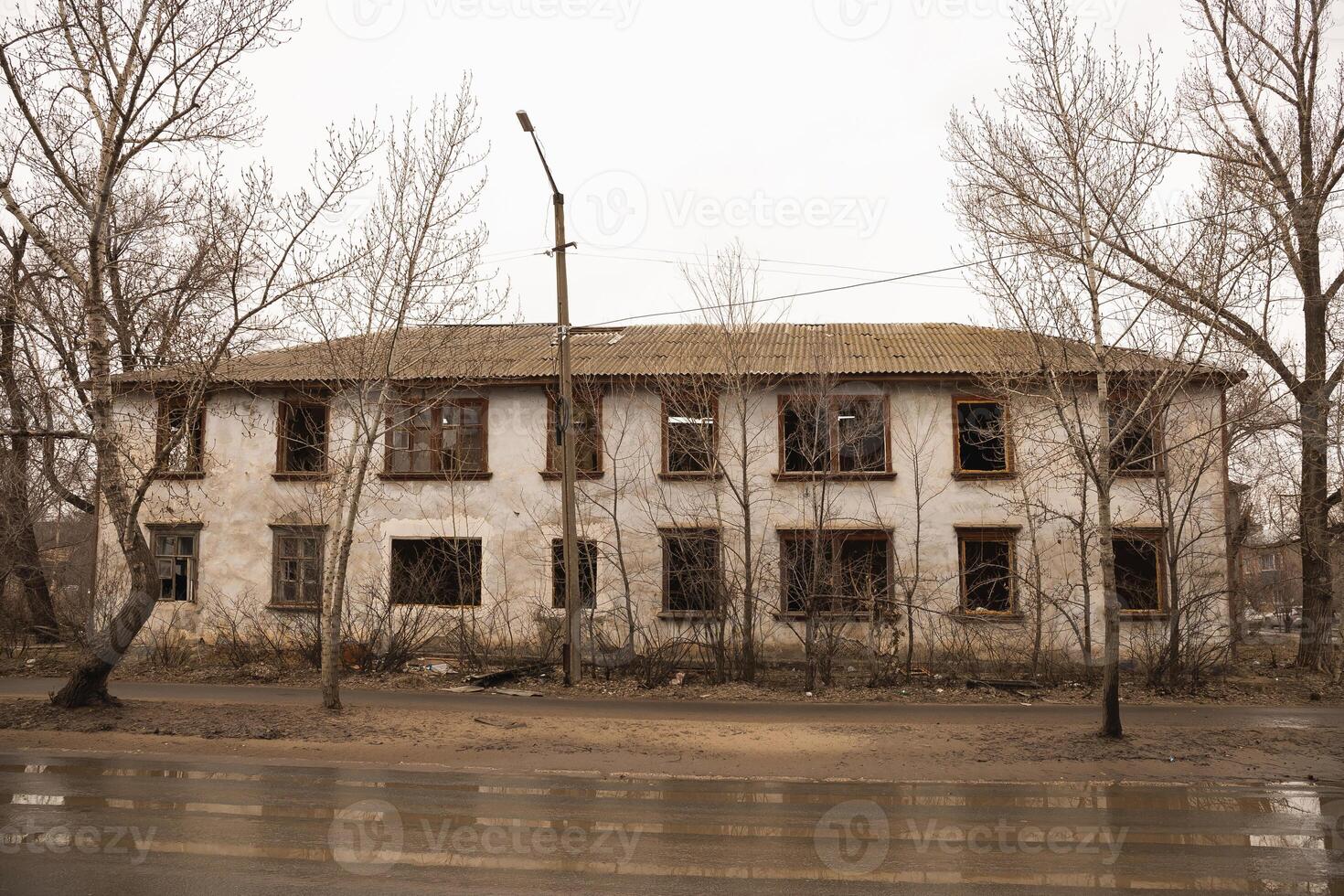 An old two storey house, partially without windows in early spring in rainy weather photo