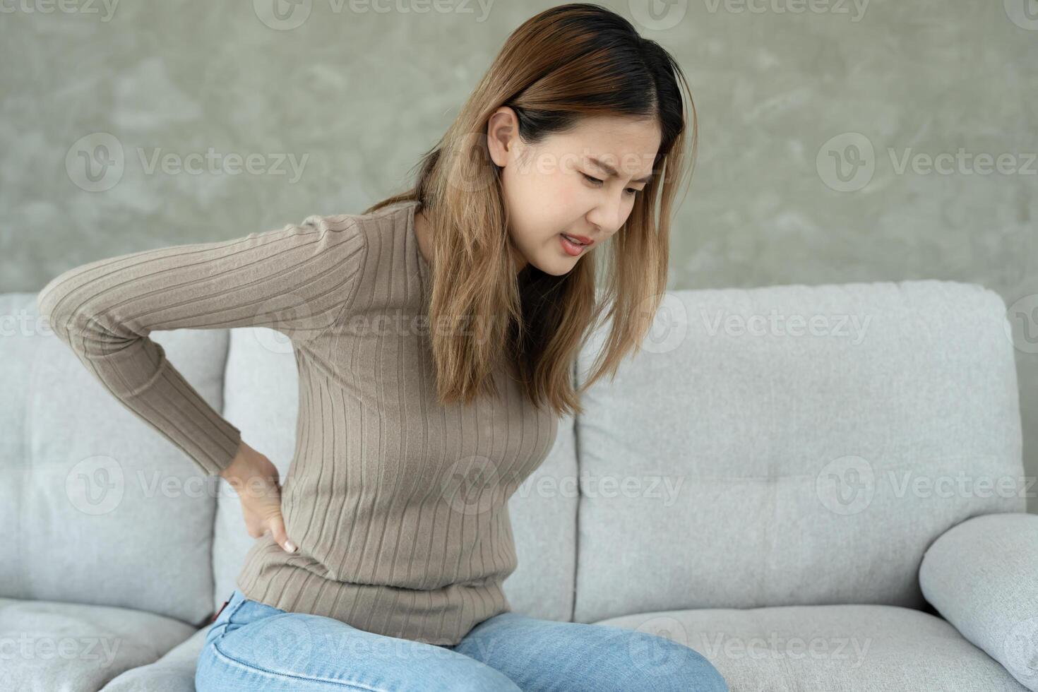 holding her lower back while and suffer from unbearable pain health and problems, chronic back pain, backache in office syndrome, scoliosis, herniated disc muscle inflammation. photo