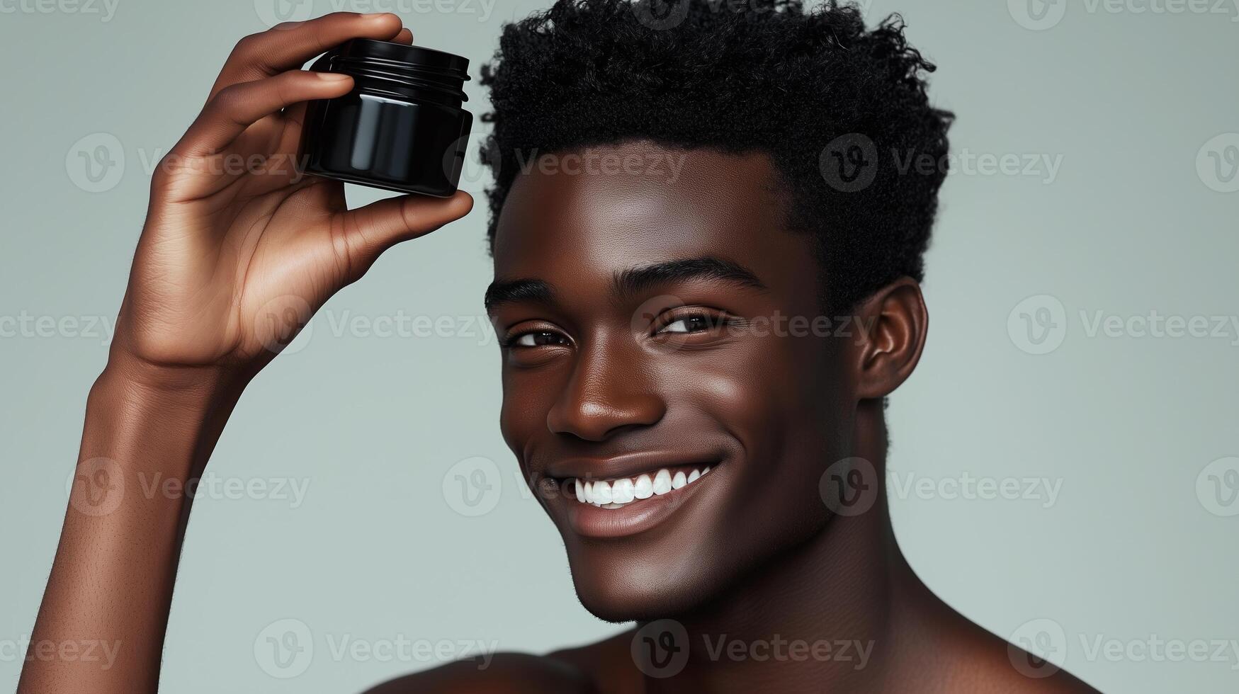 Male model with smiling expression holding black body balm in hand above head. 7 photo