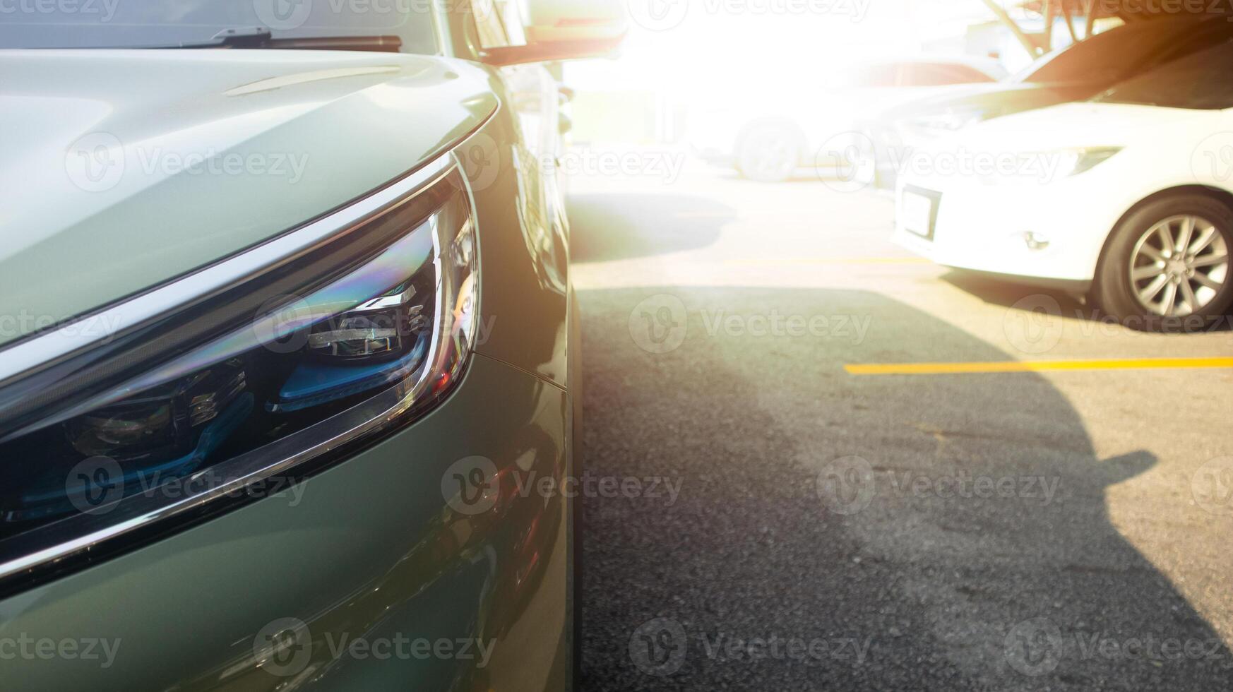 Close up of car soft green color headlight on parking lot. with blurred of other cars in parking lot under roof for background. And strong sunlight photo