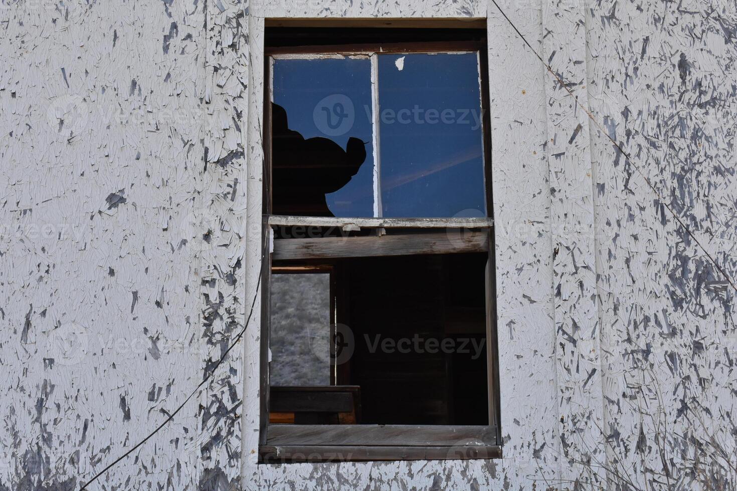 Creepy Broken Window on an Abandoned House with Peeling Paint photo