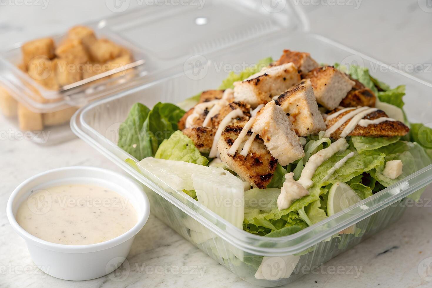Grilled Chicken Caesar Salad with Croutons and Dressing in Takeout Container photo