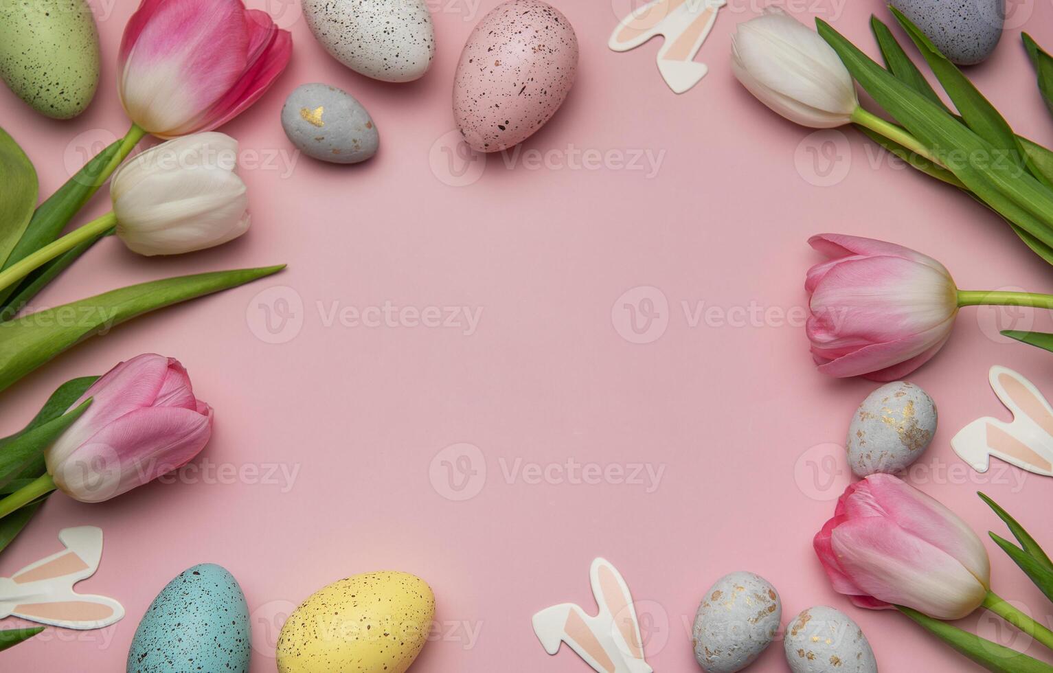 Easter eggs and tulips framing a pink background creating a festive spring atmosphere photo