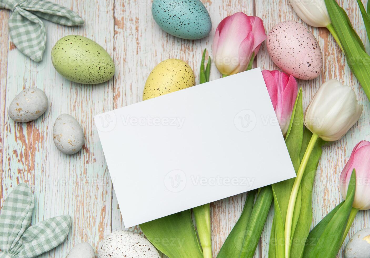 Easter eggs and tulips framing a blank card on rustic wooden background photo