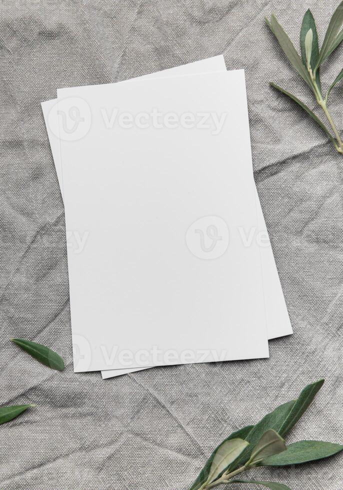 Blank card with olive branches resting on gray linen fabric photo