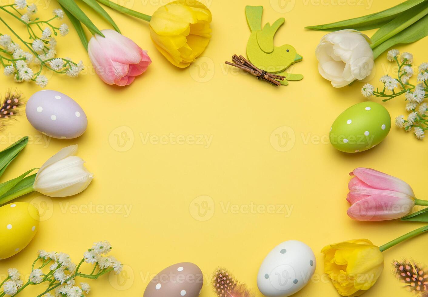 Easter eggs and tulips framing yellow background with wooden bird celebrating spring holidays photo